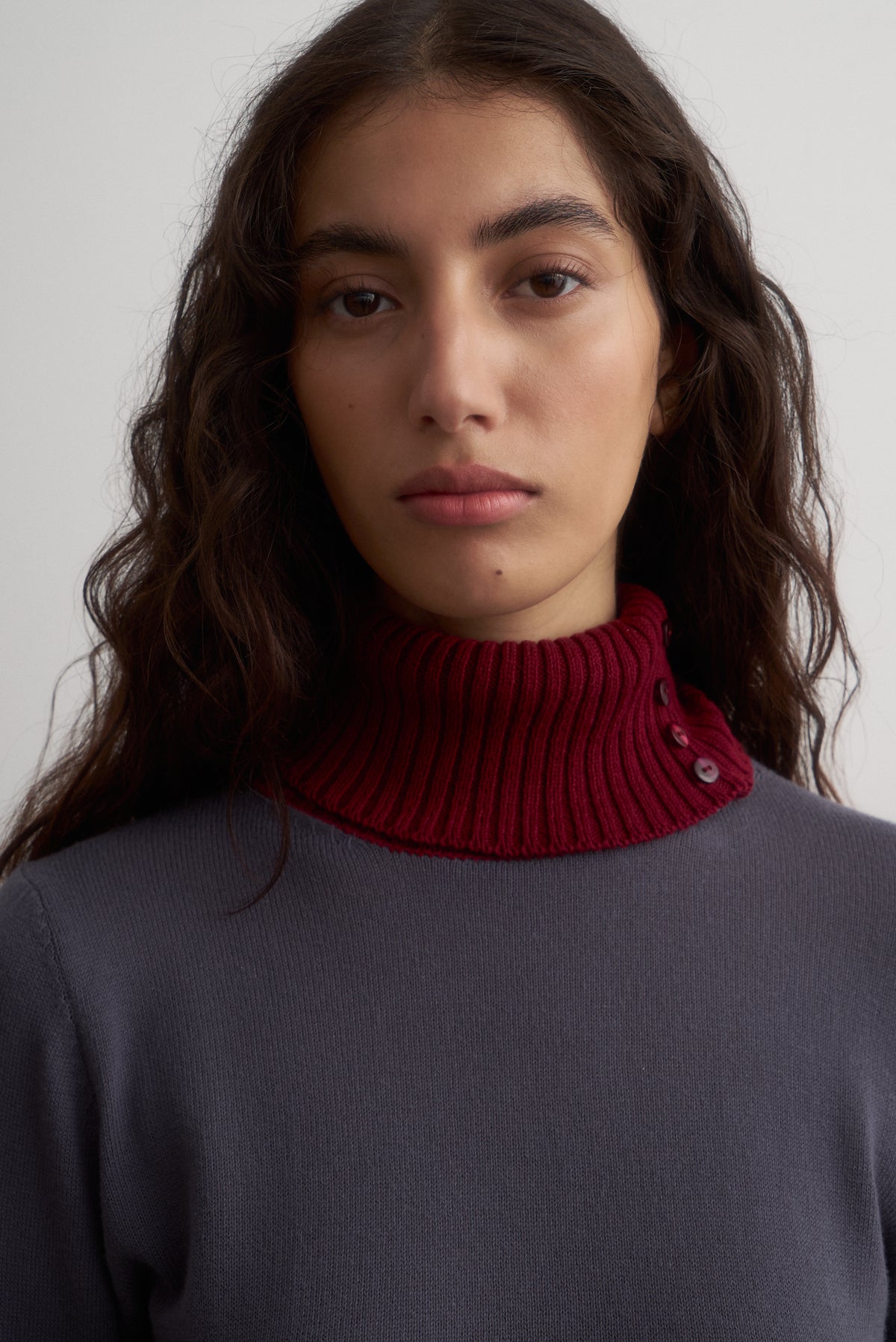 Front view of Ines grey knit top with a burgundy roll neck and matching cuffs.