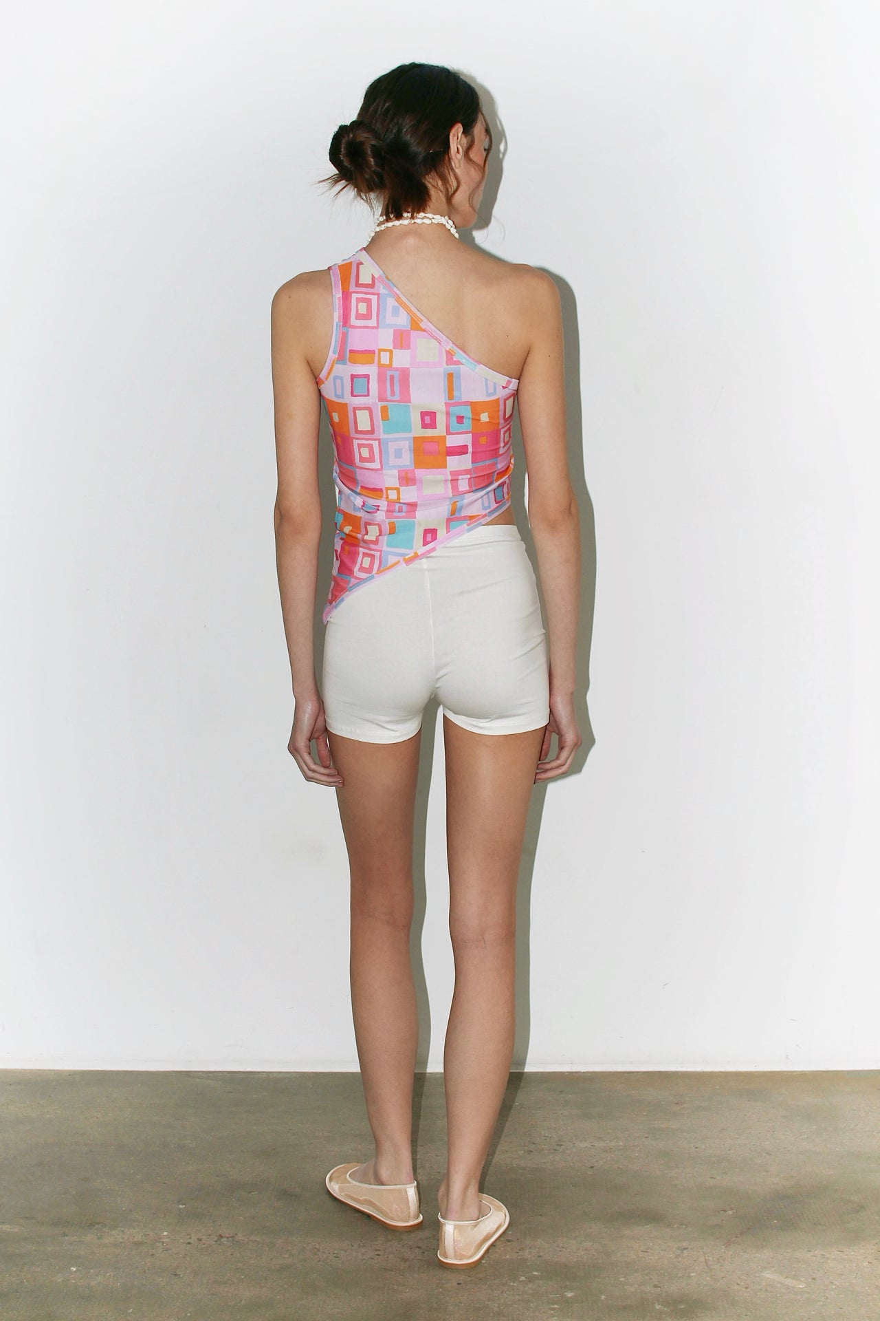 Front view of the Laura Top – colorful printed halter top with geometric pink and orange patterns, paired with a white skirt.