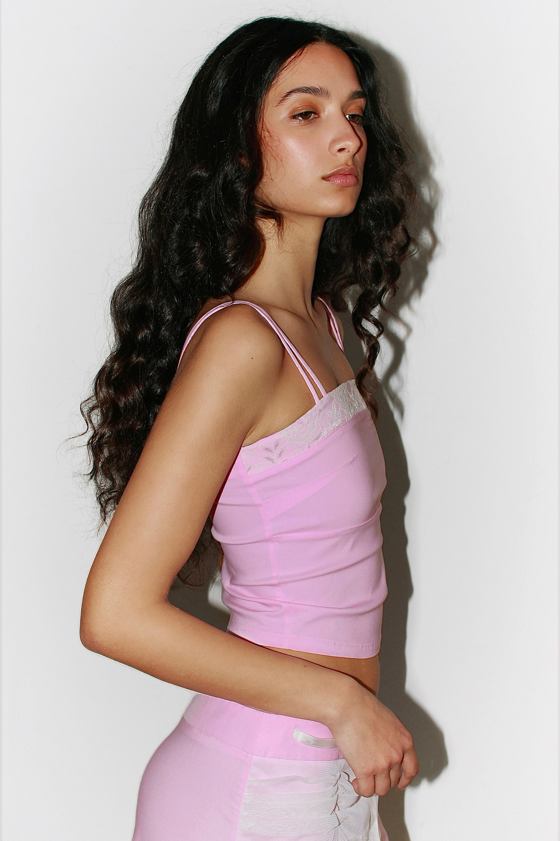 Side view of a woman in a pink top – fitted cut and elegant Mediterranean-inspired silhouette.