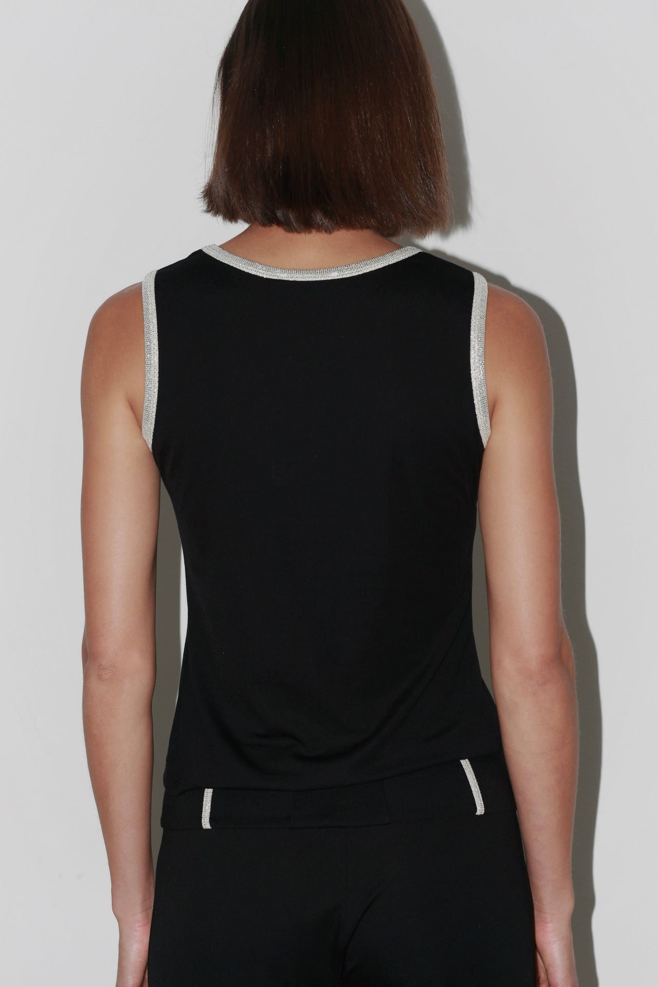 Close-up of the Jade Top – black sleeveless top with pearl-embellished neckline and elegant cut.