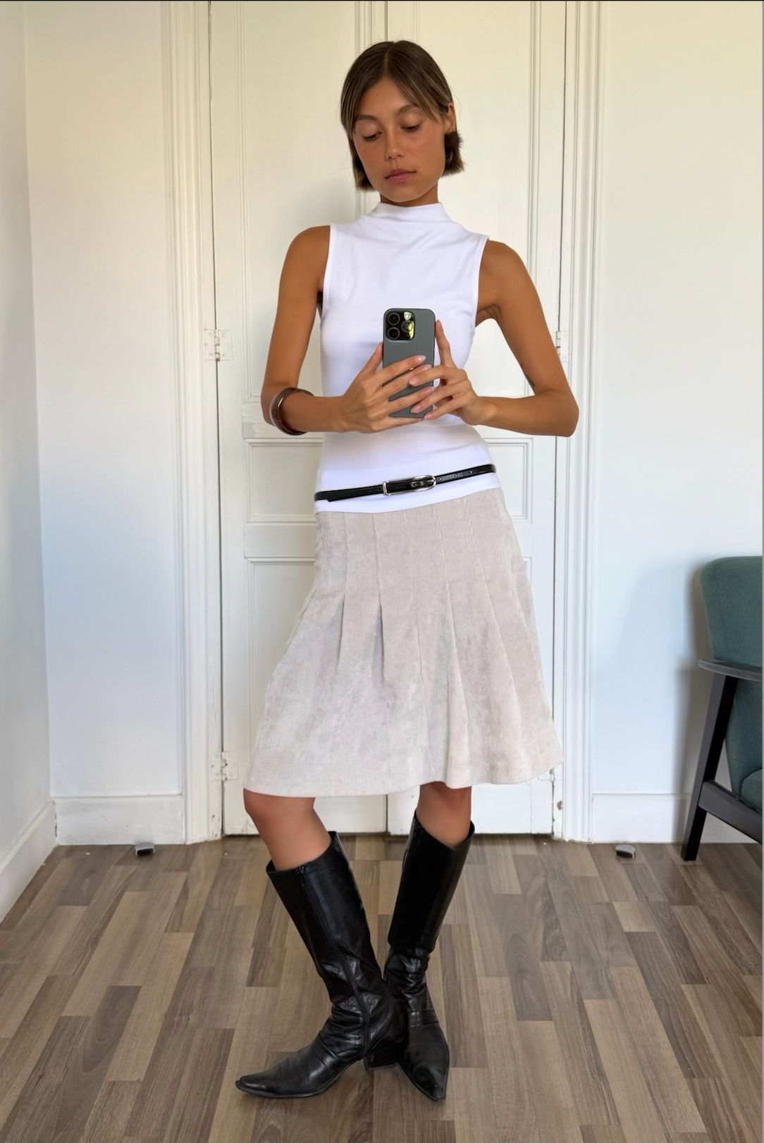 Evie ivory pleated skirt worn with a black top and boots, front view