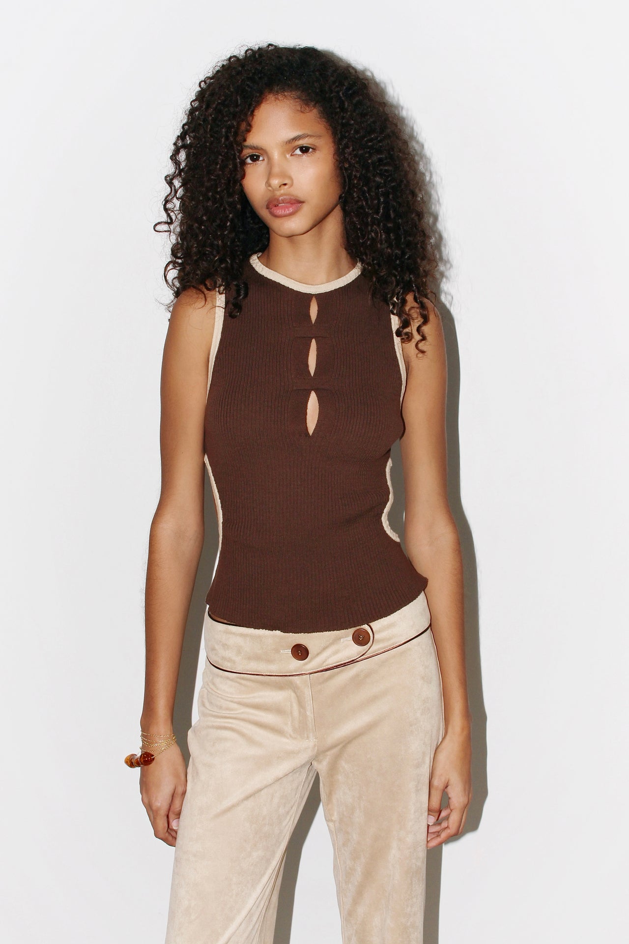Front view of the Ana Top in brown ribbed knit, featuring a high neckline with three teardrop cutouts and contrast beige trim along the edges.