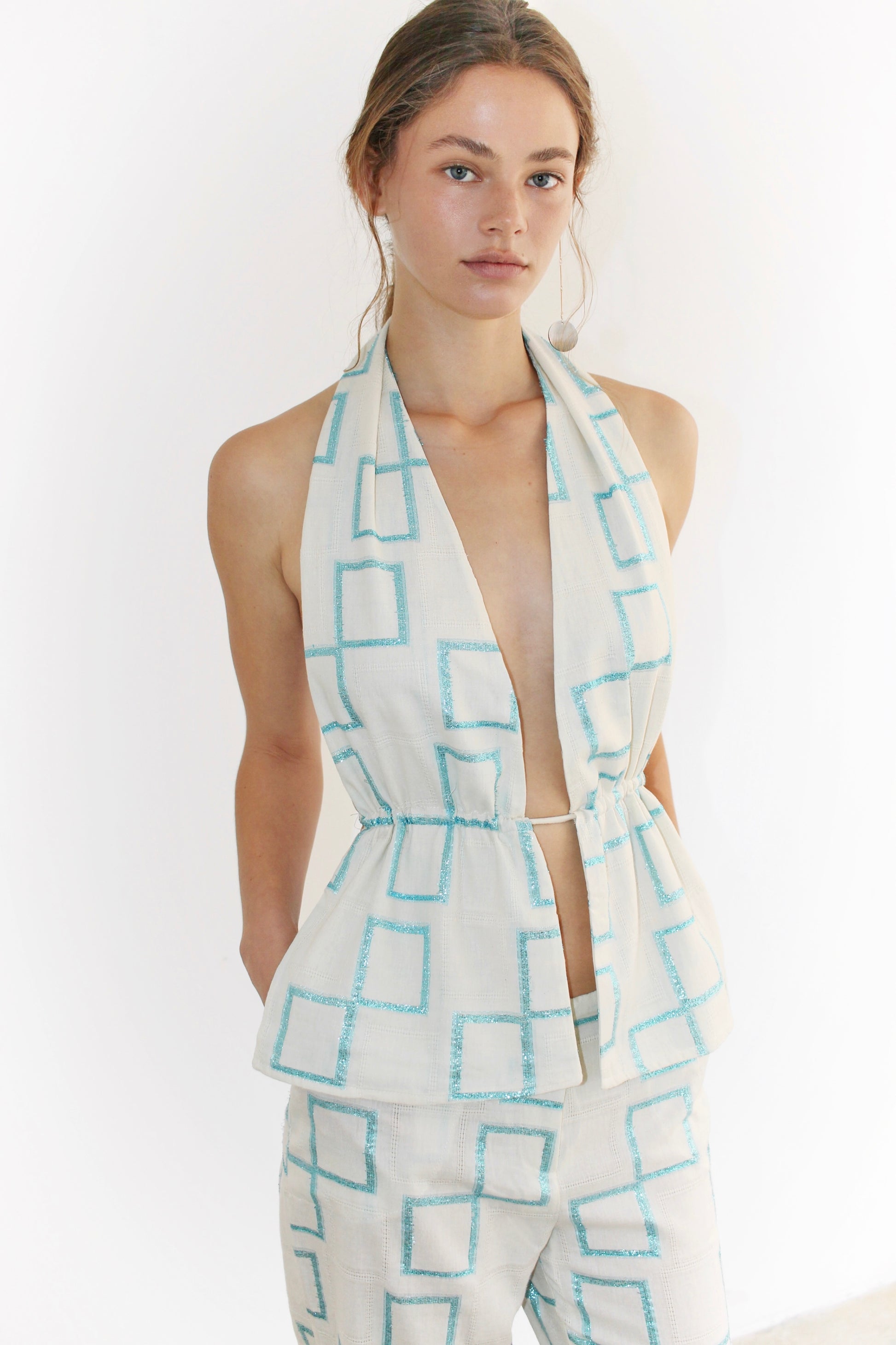 Three-quarter front view – high-neck blue printed top with cross ties, soft pastel tones and elegant lines.