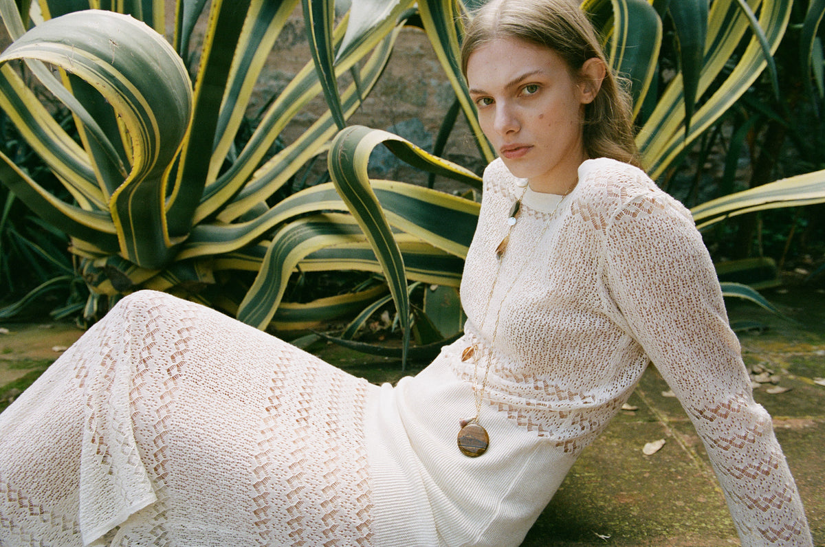 Consuelo white shirt styled with dark trousers against a wood-panelled backdrop.