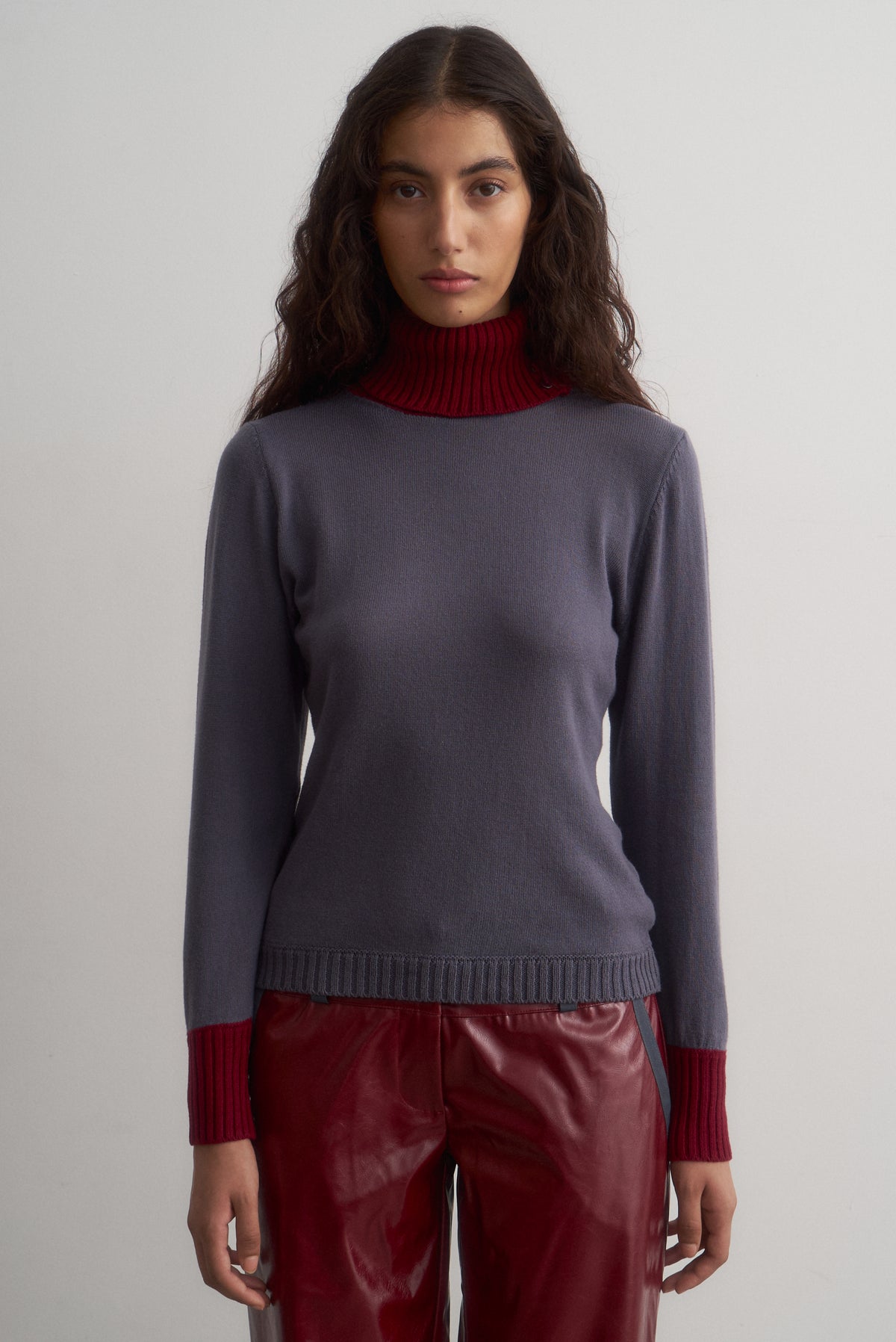 Front view of Ines grey knit top with a burgundy roll neck and matching cuffs.