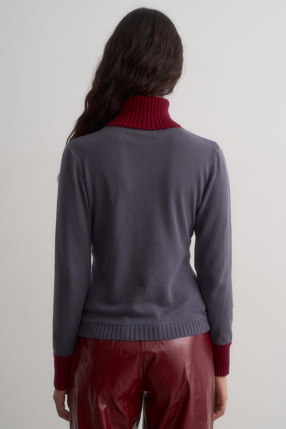 Rear view of Ines grey knit top showing its burgundy collar and ribbed hem.