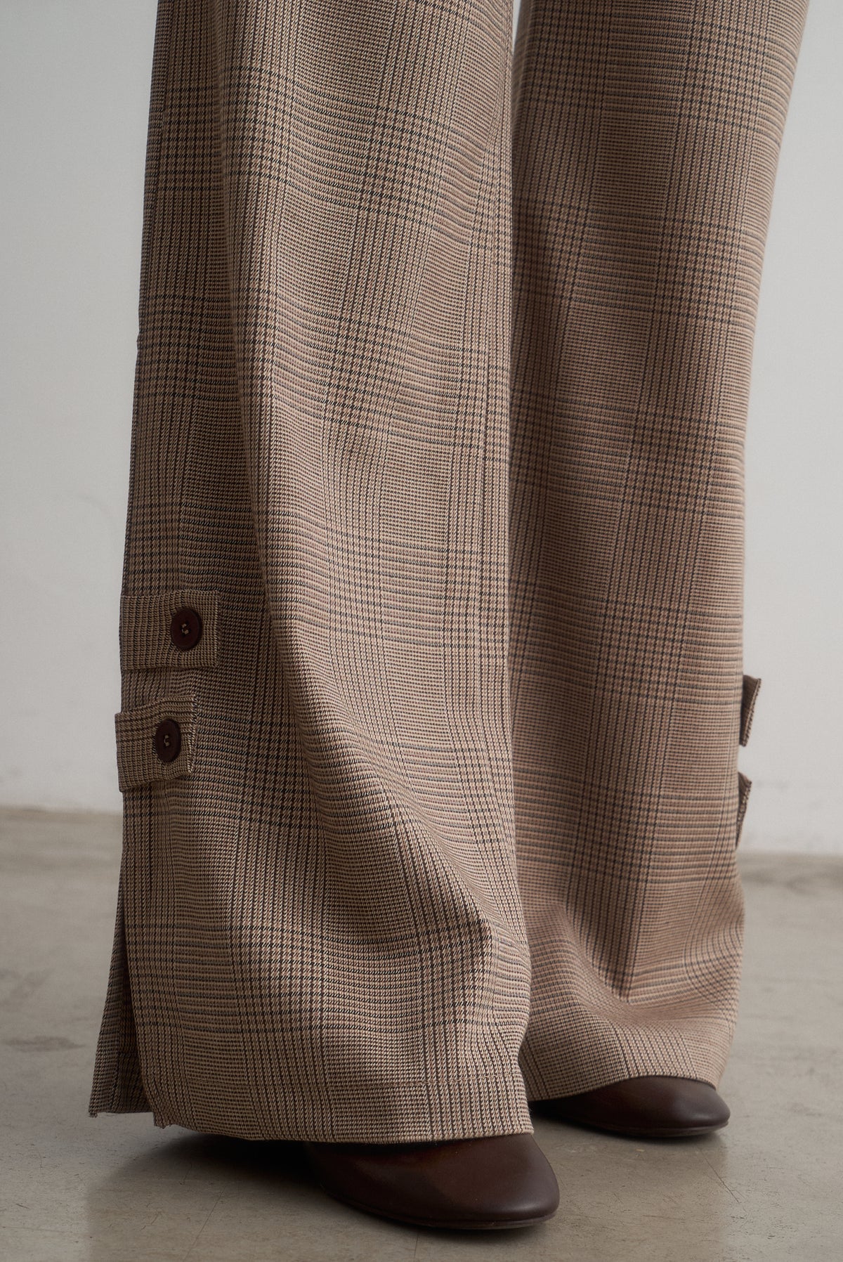 Close-up of Lavinia checked trouser hems showing decorative buttoned tabs.