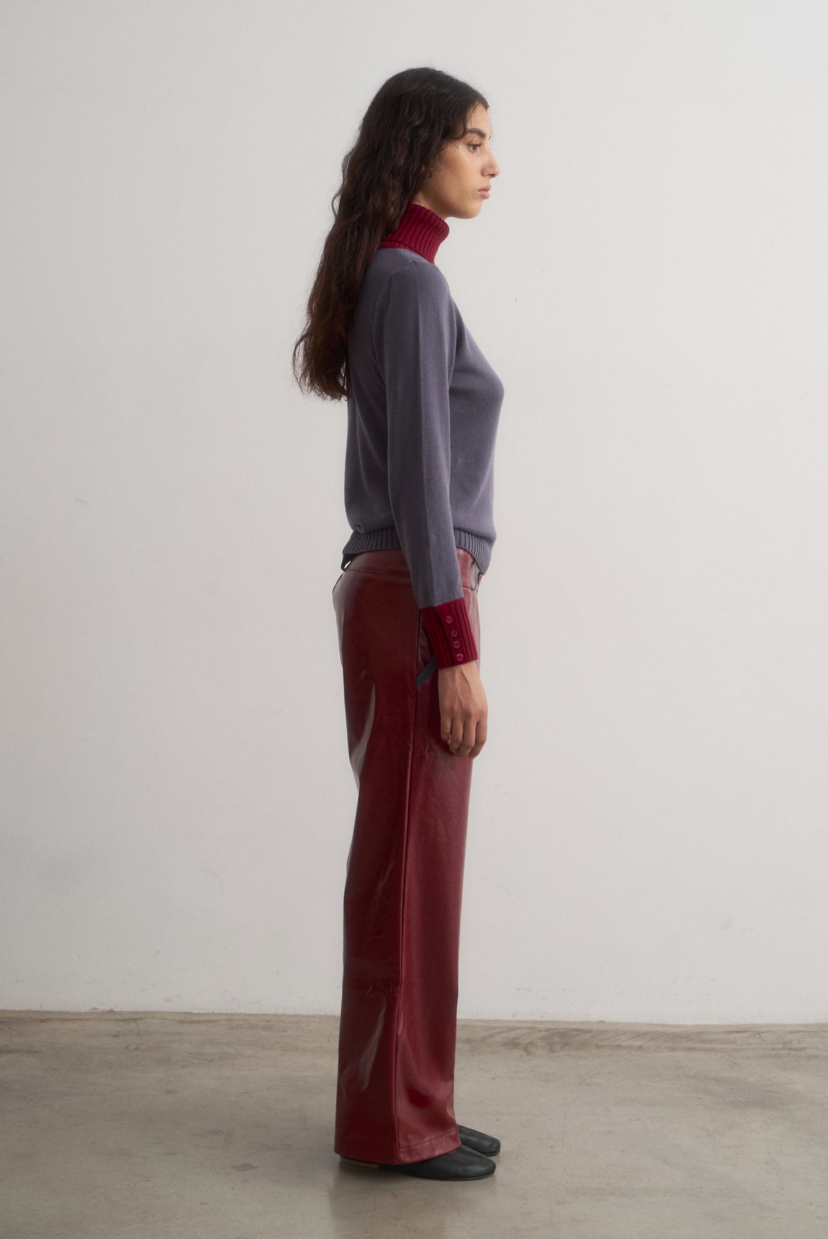 Full-length side view of Ines grey and burgundy knit top styled with burgundy trousers.