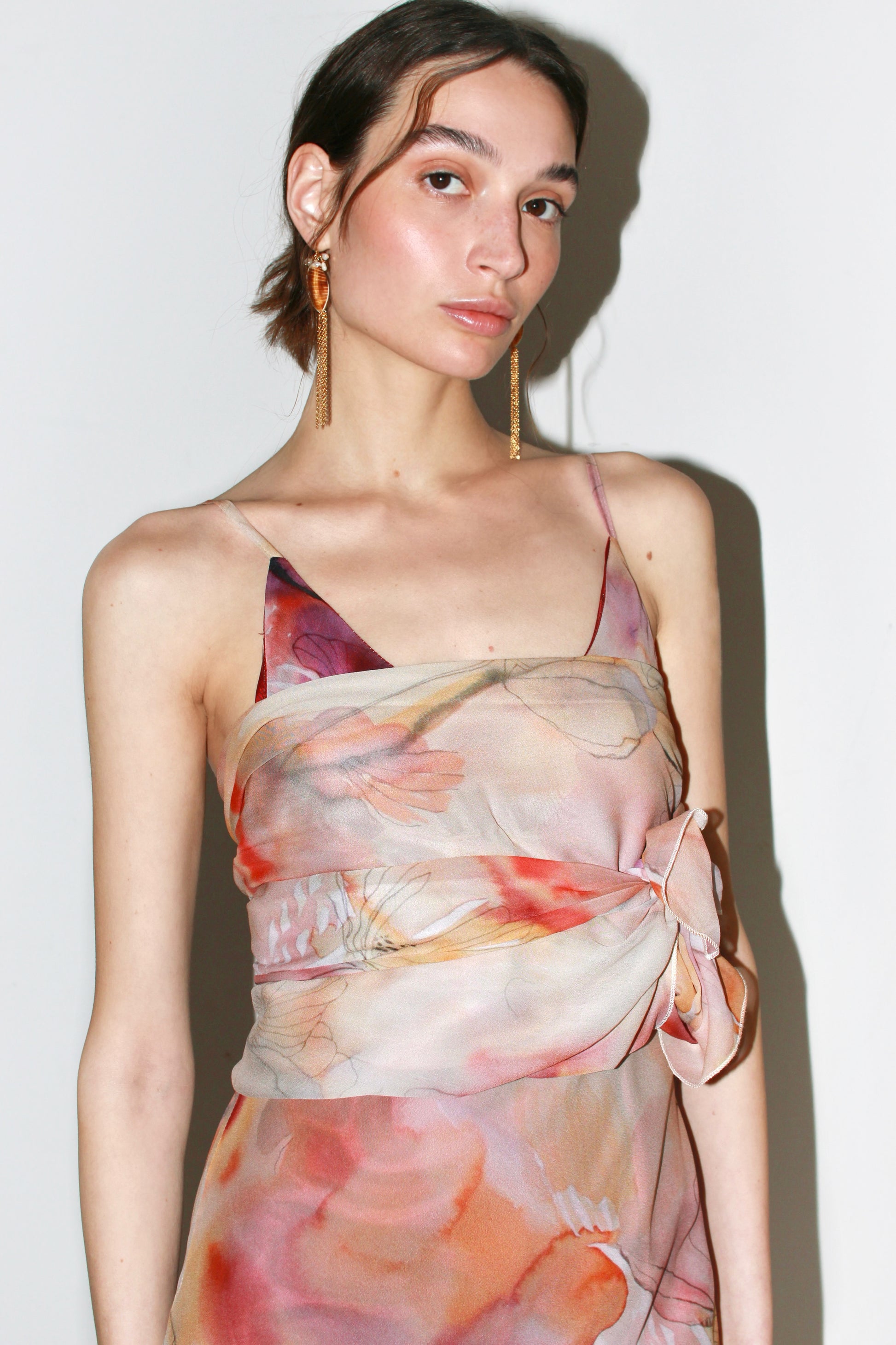Close-up detail of the Alma Dress's viscose fabric, highlighting the abstract floral pattern in soft pink and orange tones.