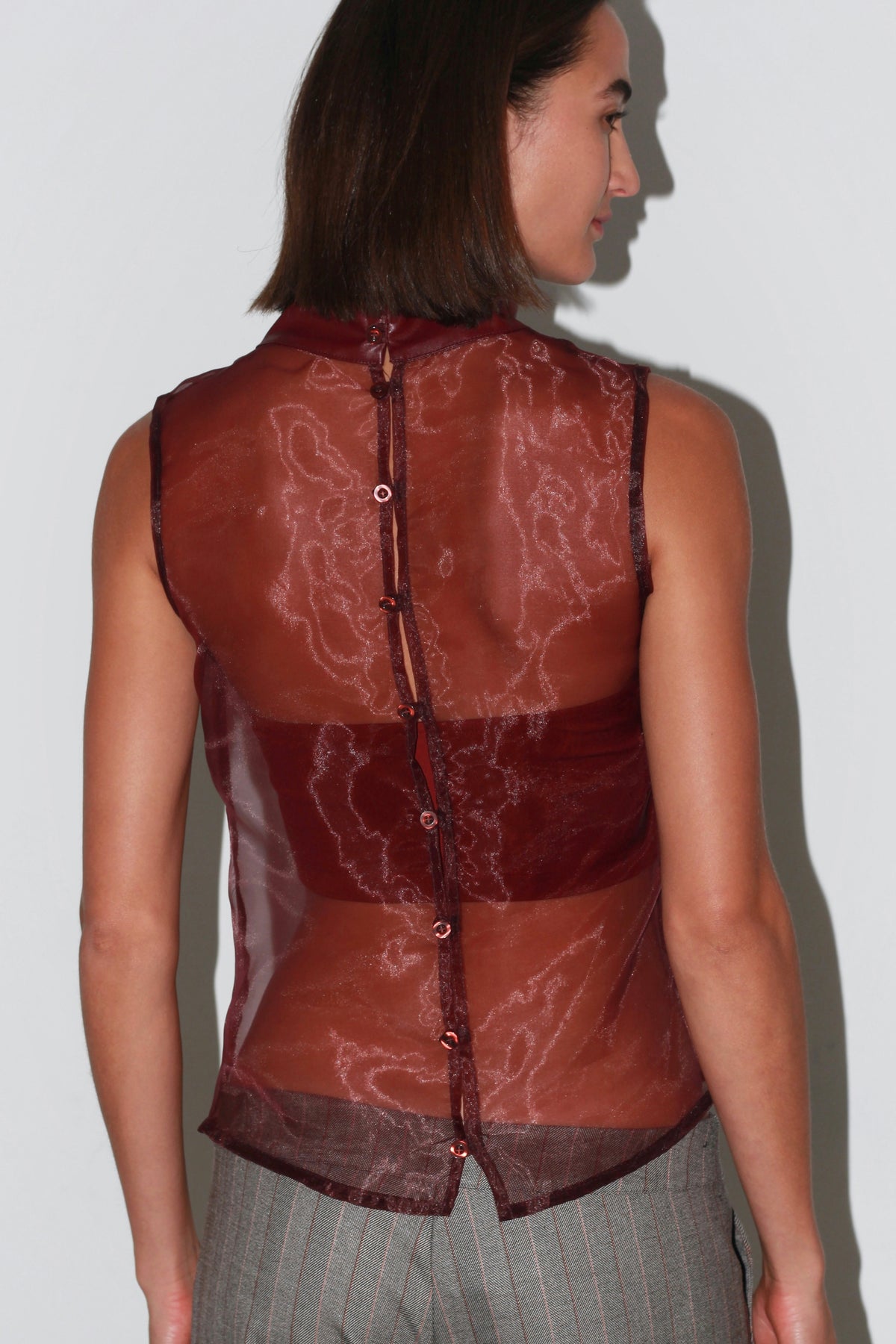 Front view of Fiorella sheer burgundy top with a matching bandeau and grey trousers.