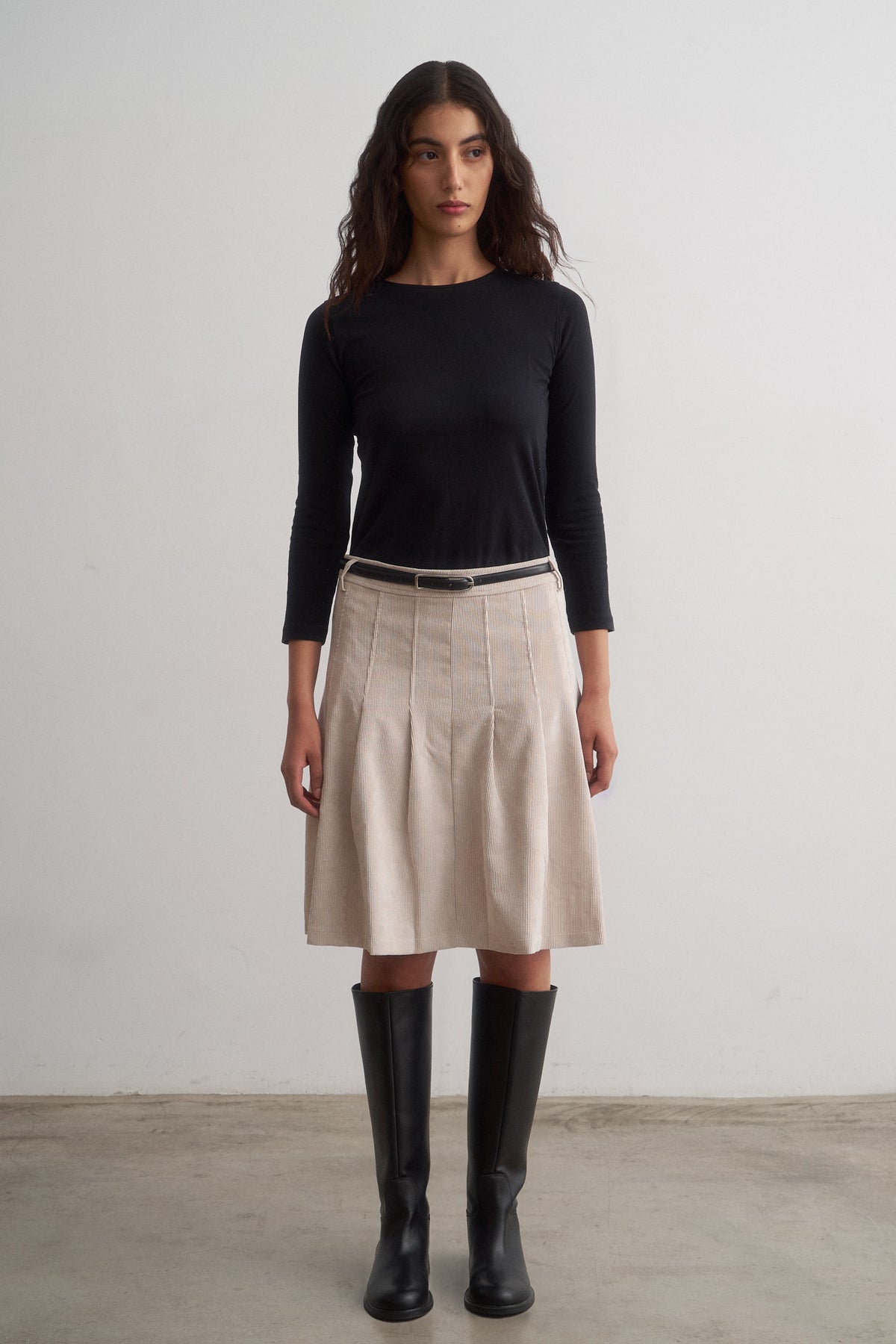 Evie ivory pleated skirt worn with a black top and boots, front view