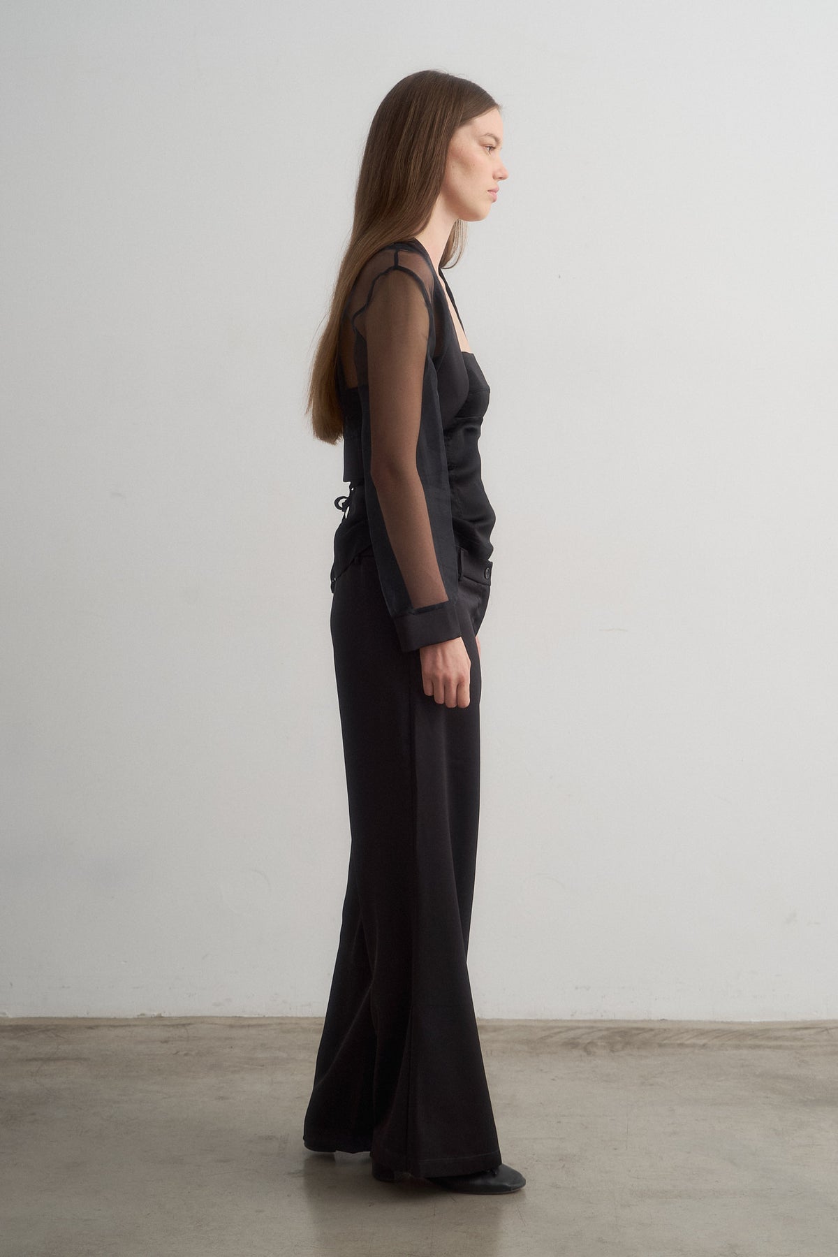 Lavi black wide-leg trousers worn with a sheer jacket, side view