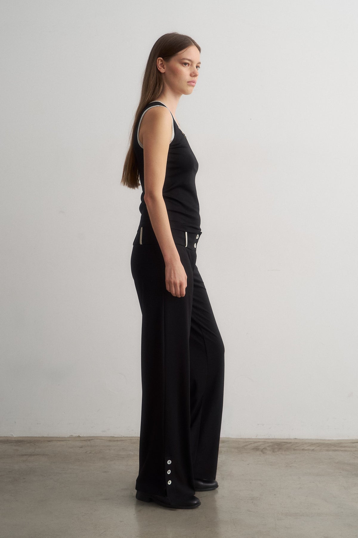 Jade black sleeveless top worn with Zeynep black trousers, side view
