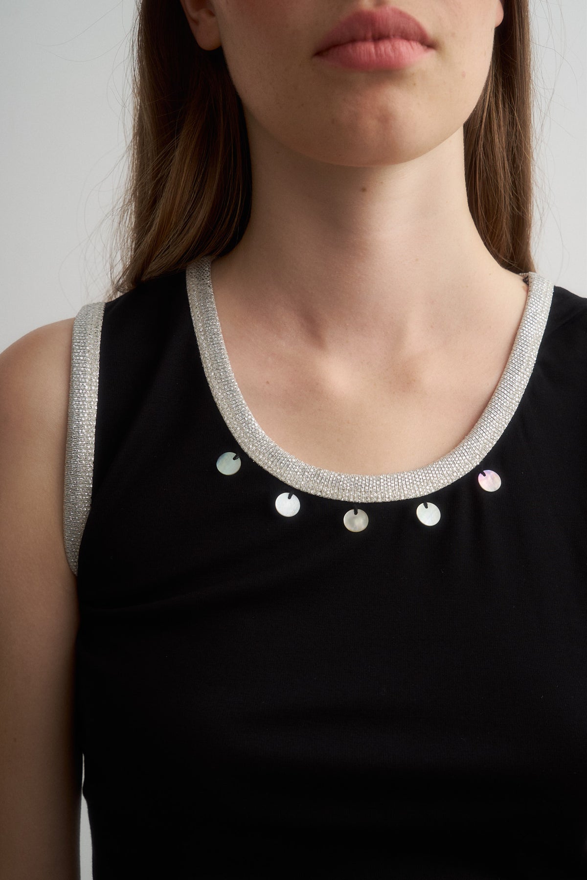 Jade black top, close-up of metallic neckline trim and shell details