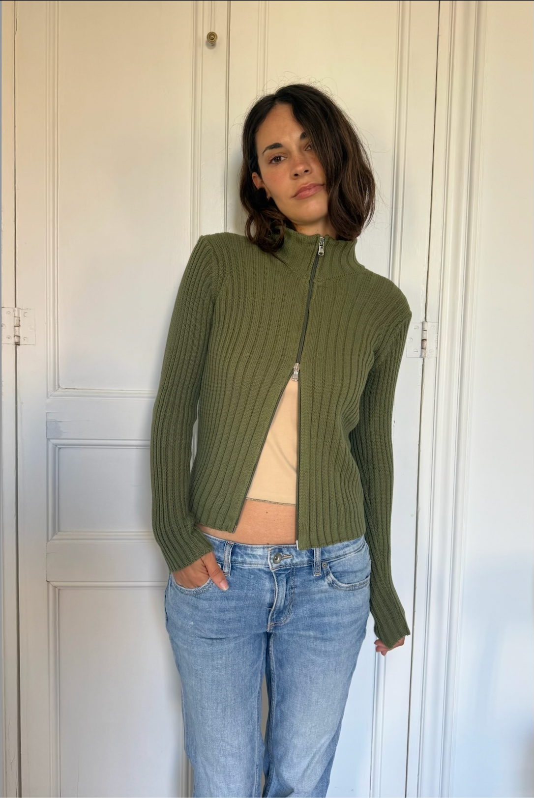 Barca green zip top styled with blue jeans indoors